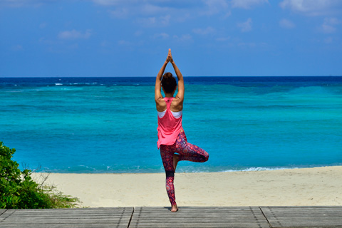 a lady striking a yoga pose on the beach